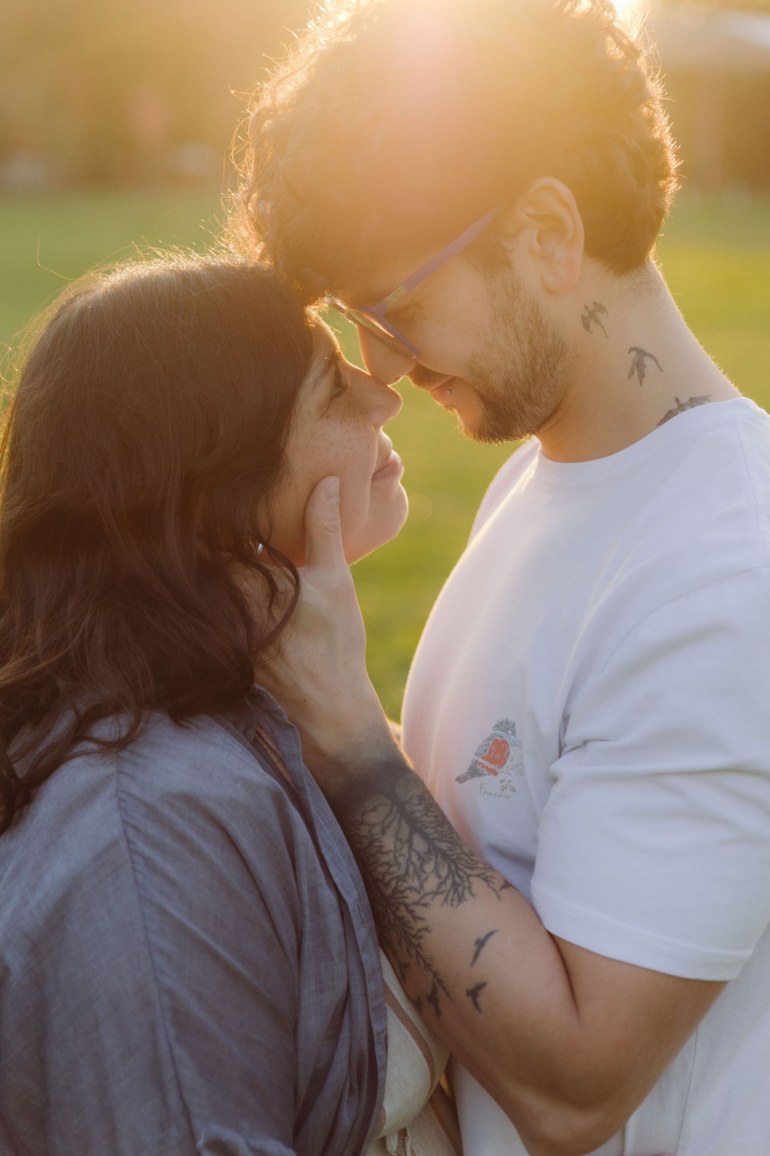 Romantic couple almost kissing face to face in warm golden sunset light in park.