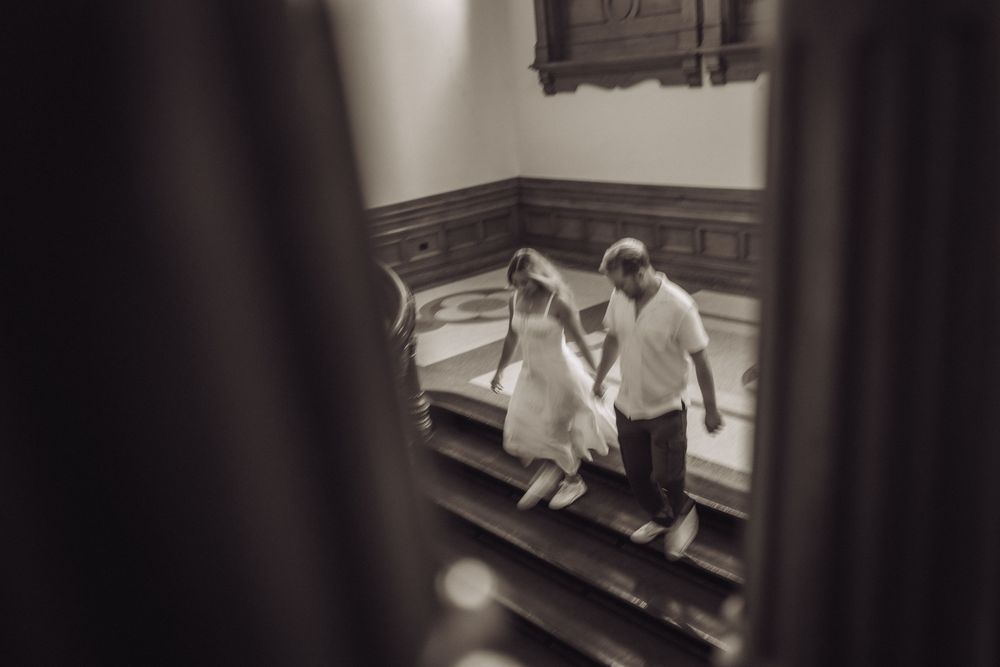 Black and white photo of a couple holding hands on church stairs during a wedding ceremony.