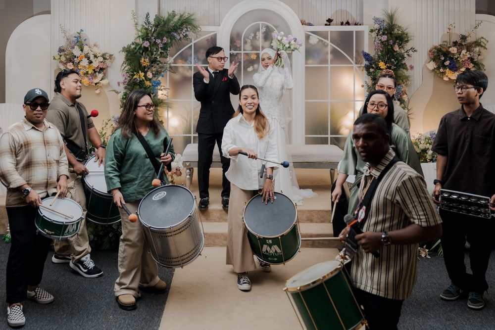 Indoor wedding ceremony with drummers performing for guests near a floral altar.