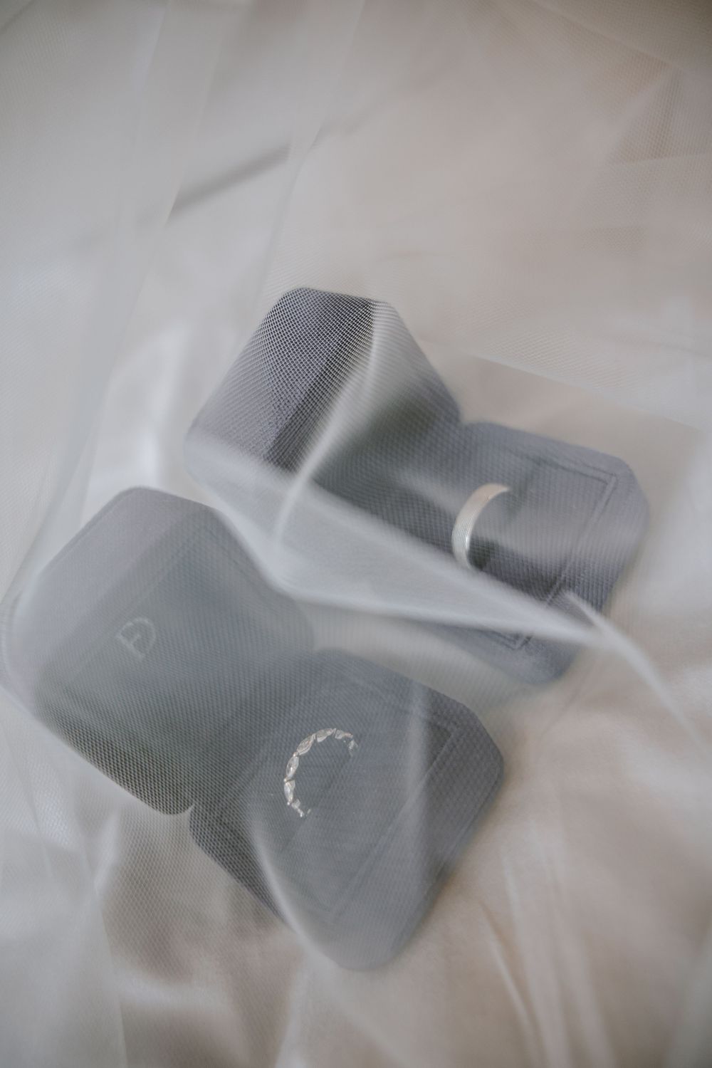 Gray dumbbells wrapped in clear plastic packaging on a white fabric background.