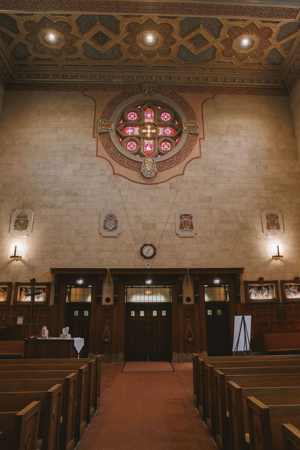 Historic church interior with ornate stained glass rose window, wooden pews, and decorative ceiling.