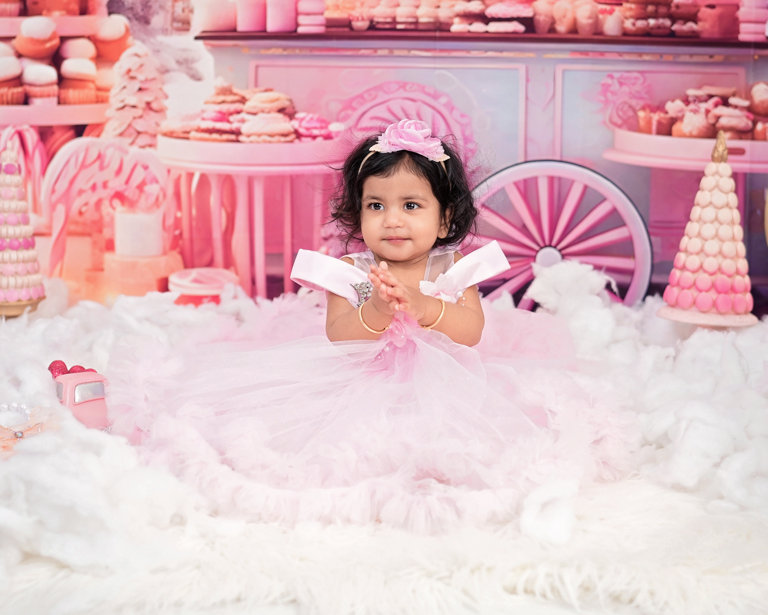 Adorable toddler girl in pink tutu dress at a pink candy-themed first birthday cake smash photo shoot.
