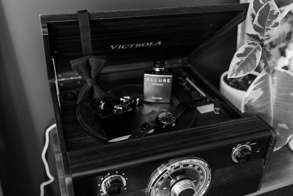Vintage Victrola record player with cologne bottle in black and white photo.
