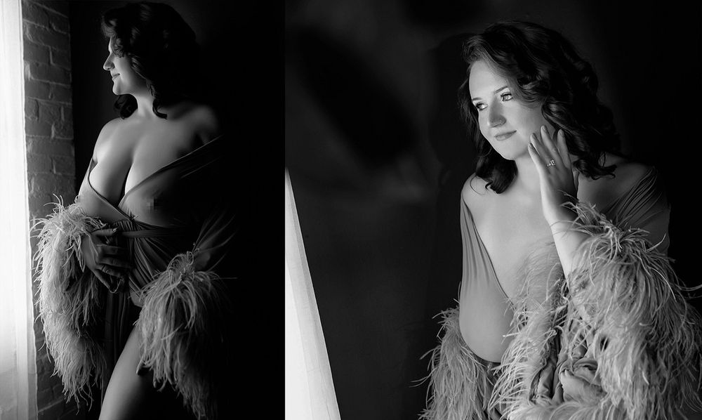 Black and white boudoir photo of a woman in a feathered robe posing elegantly in soft studio lighting.