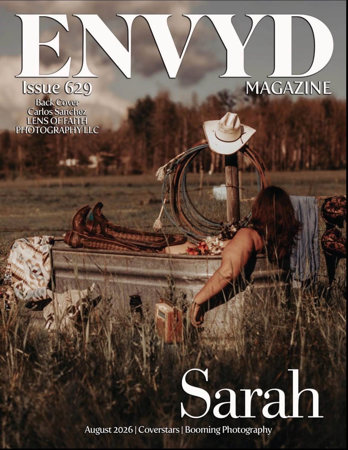 Magazine cover from ENVYD Magazine features a rustic outdoor scene with a cowboy hat, coiled rope, and a woman leaning over a weathered tub