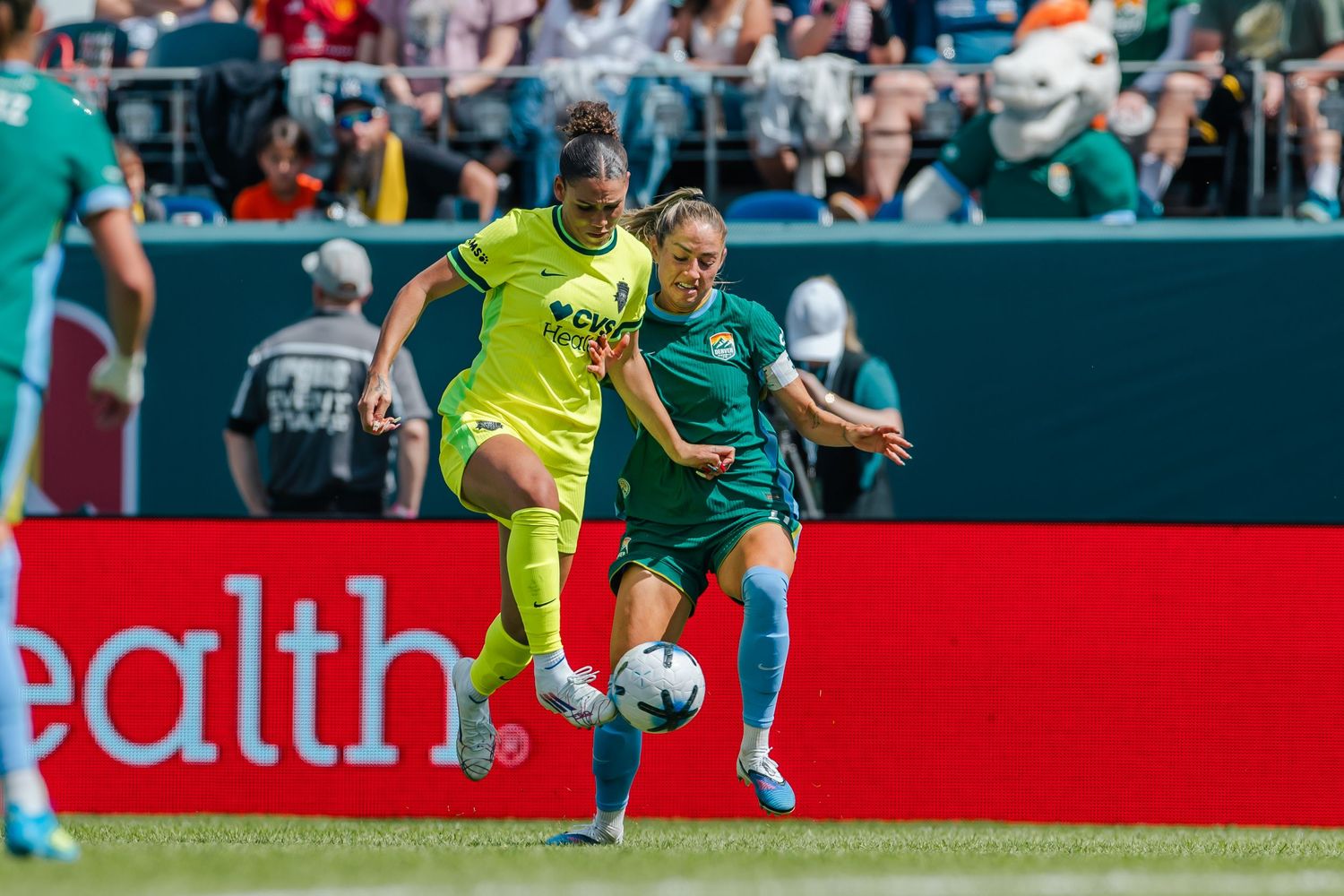 Two female soccer players compete for the ball during a professional women's soccer match on a green field.