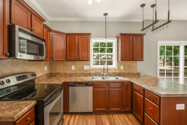 Residential kitchen with wood cabinetry and stainless steel appliances photographed for real estate marketing