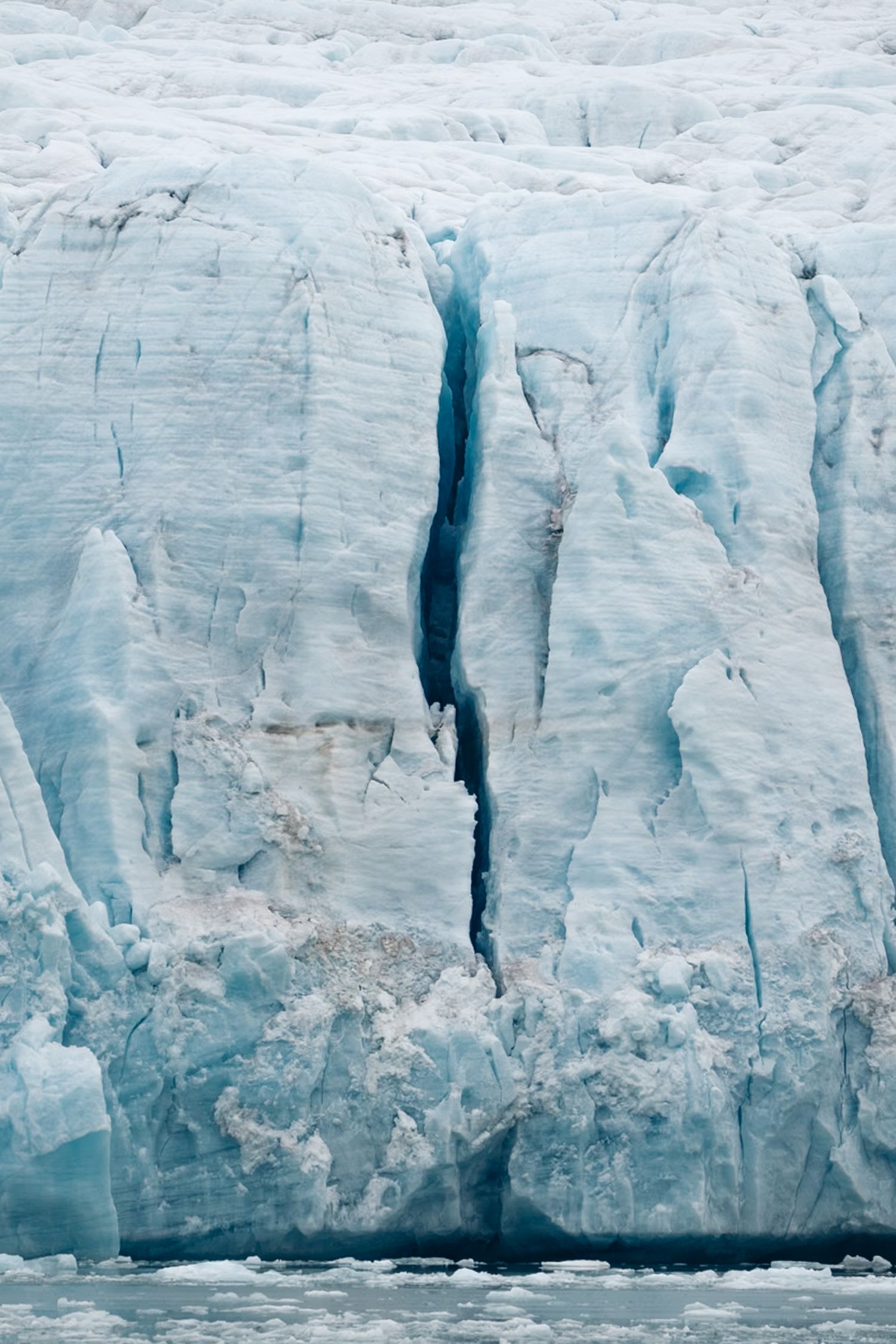 Fracture verticale d'un bleu profond dans un front de glace au Svalbard