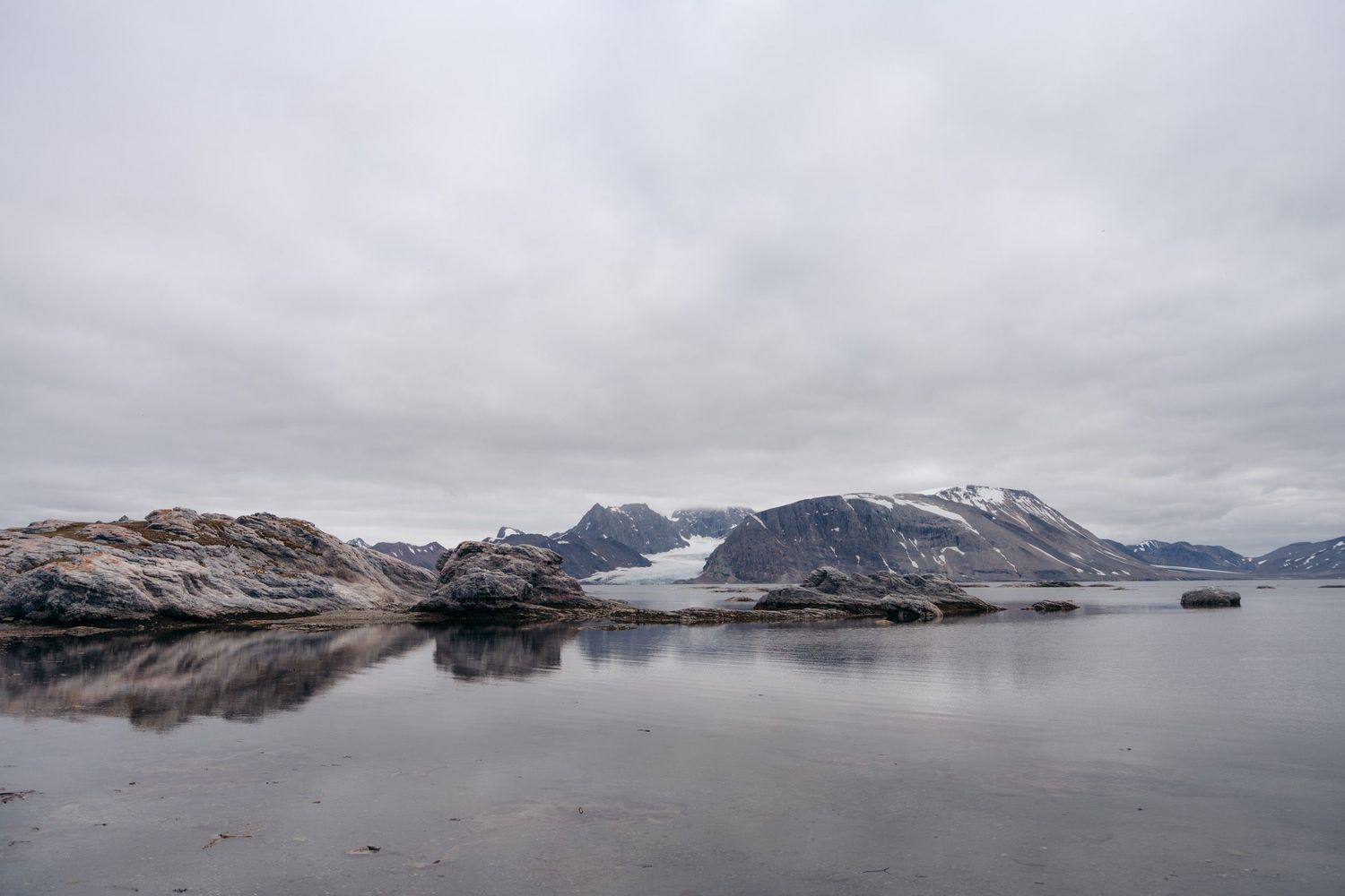 Baie calme de Gnålloden bordée de montagnes enneigées, glacier au fond