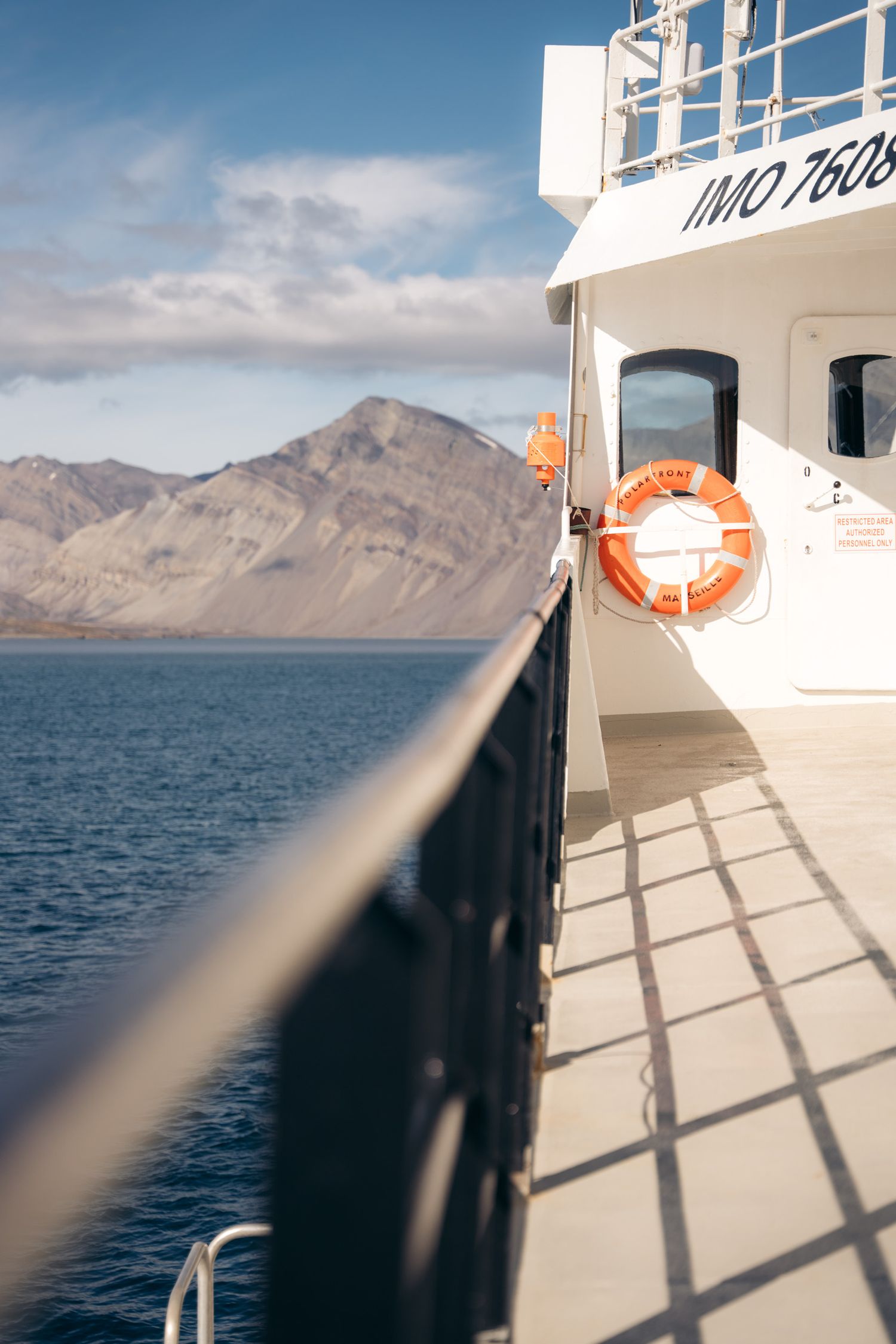 Coursive du Polarfront et sa bouée orange, montagne du Svalbard éclairée à gauche