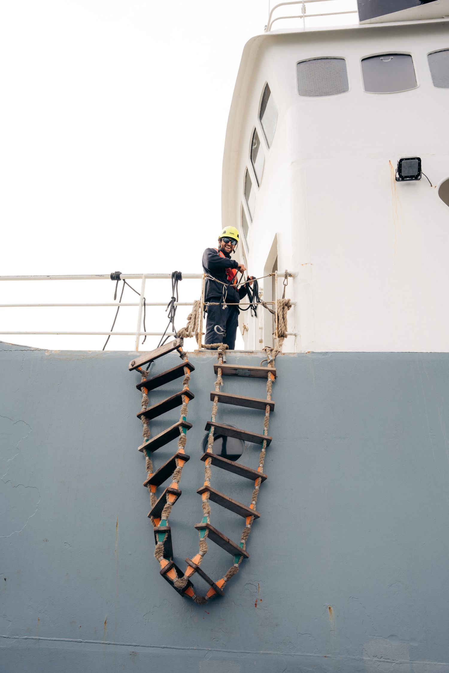 Marin au casque jaune remontant l'échelle de coupée le long de la coque du Polarfront