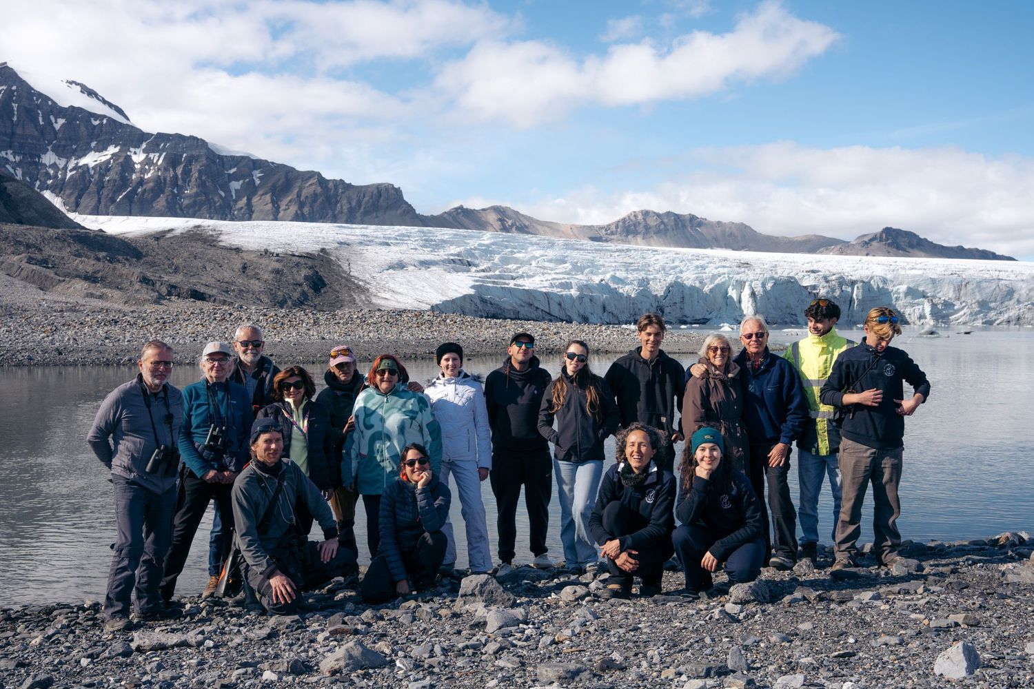 Une vingtaine de passagers sur la grève devant un front glaciaire étalé, au Svalbard