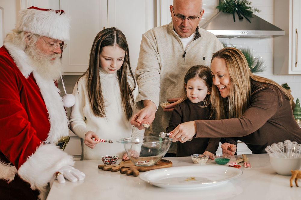 Family baking Christmas cookies with Santa Claus in a festive kitchen holiday scene.