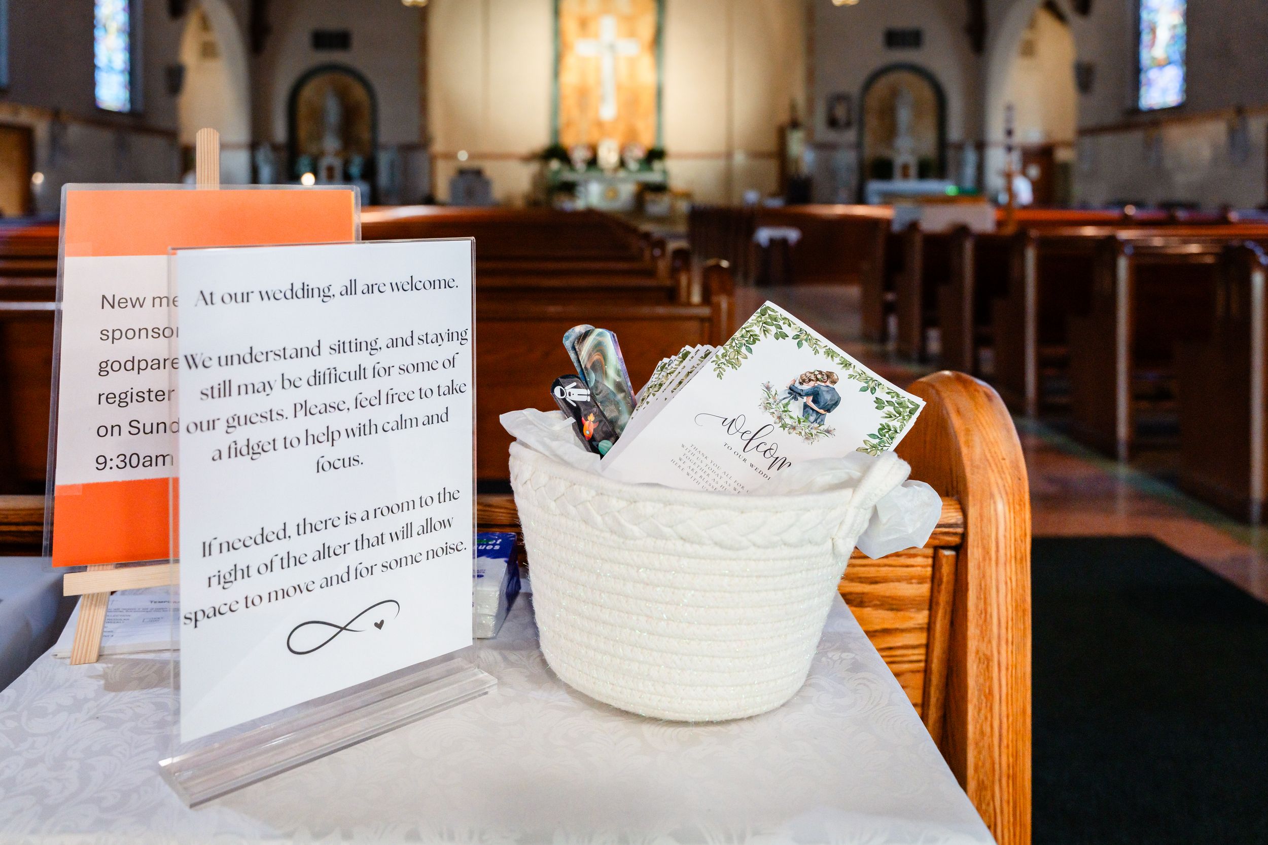 Church wedding welcome basket with programs and sign on pew at ceremony venue.