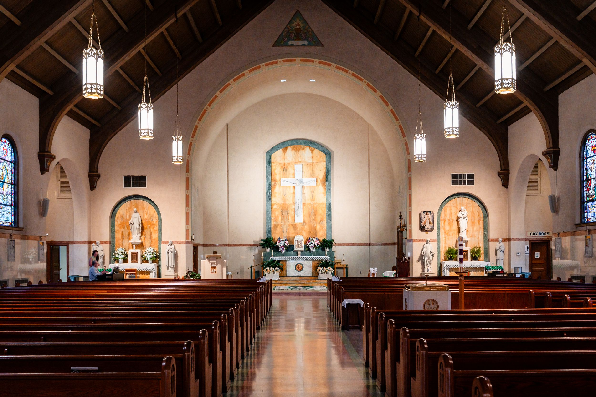Empty church interior with wooden pews, stained glass windows, and decorated altar before wedding.