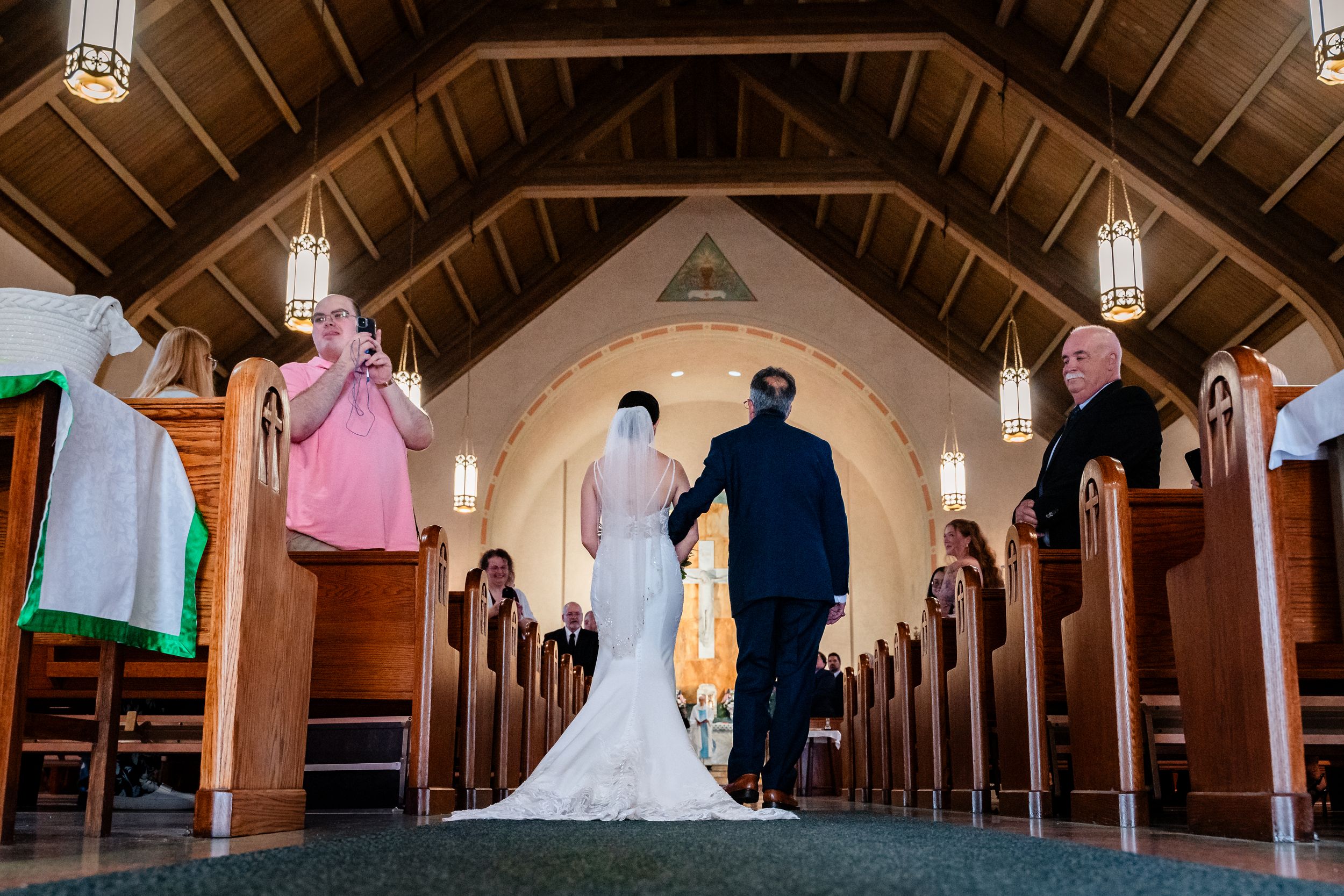 Bride walking down church aisle with escort during wedding ceremony.