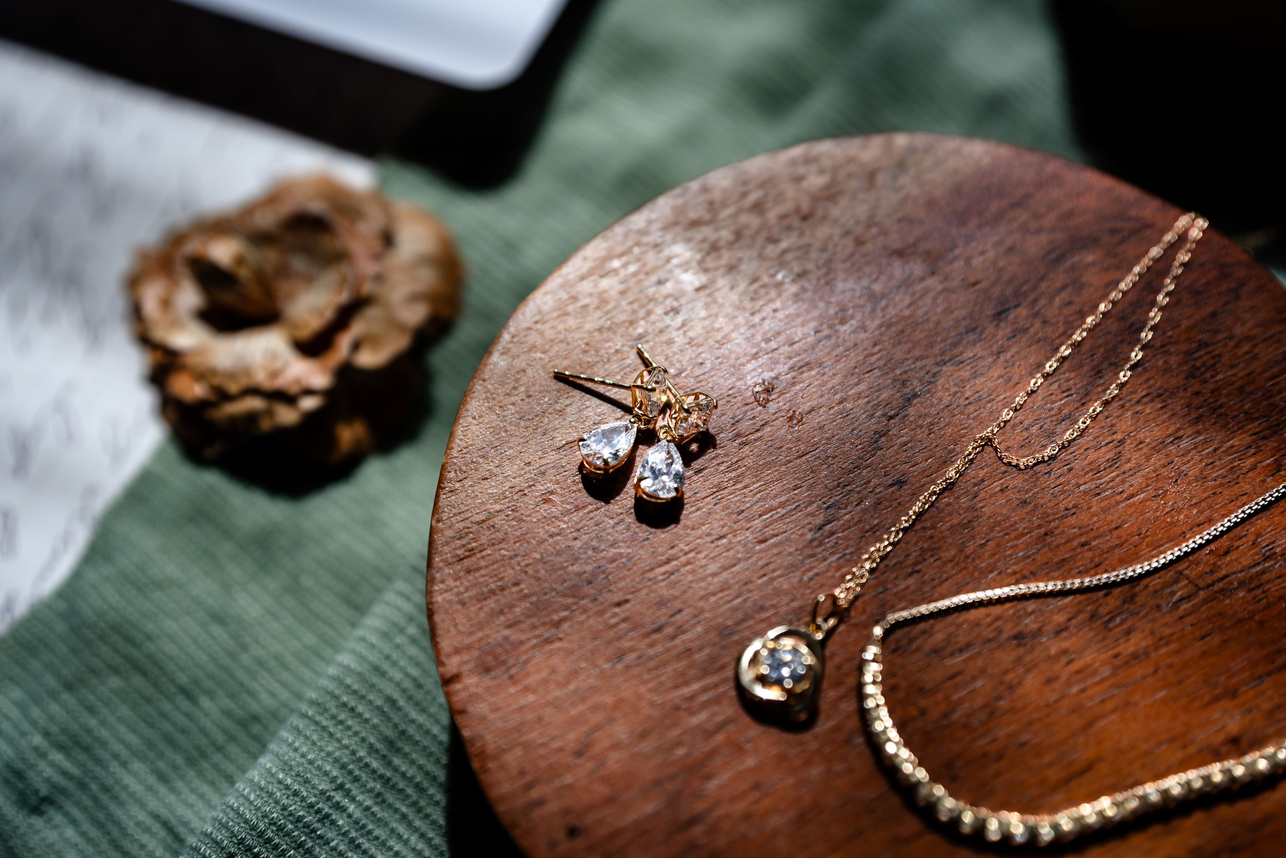 Gold jewelry set with diamond pendant necklace and star earrings displayed on a wooden tray.