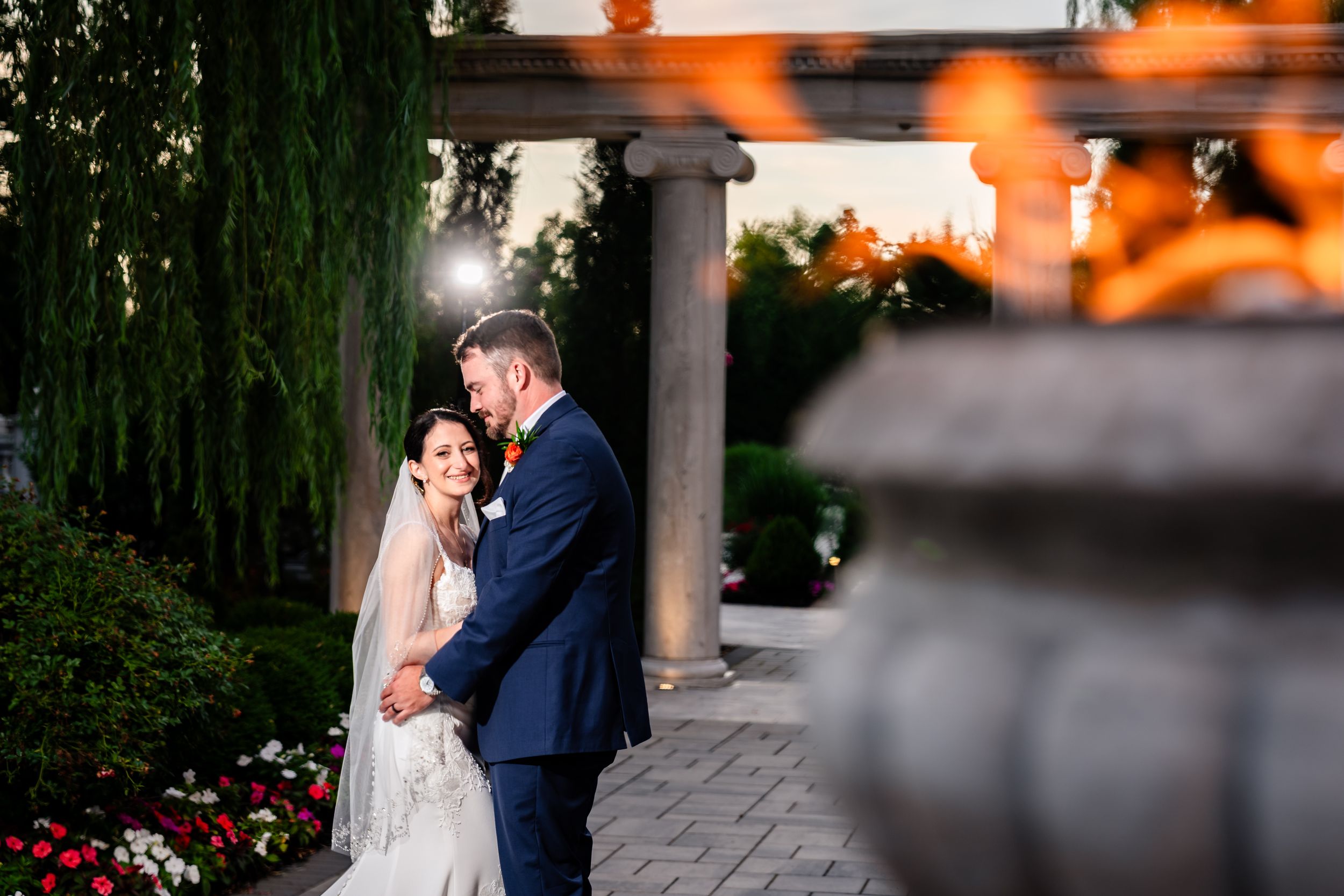 Bride and groom share romantic moment in garden at golden hour sunset.