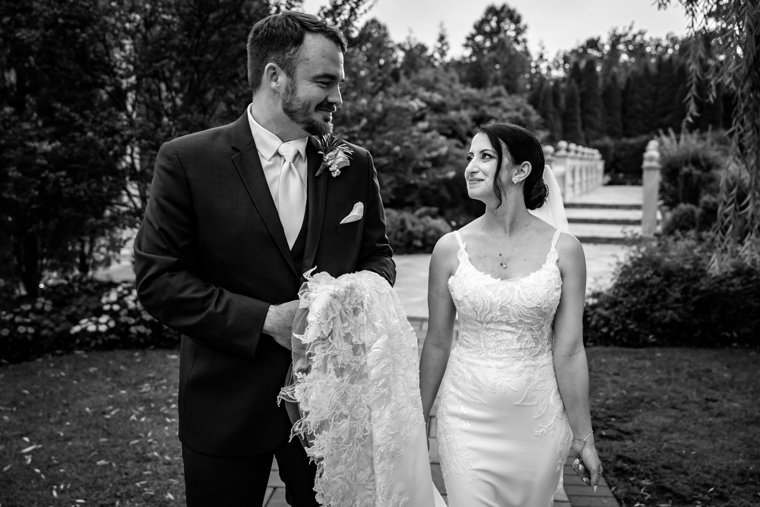 Bride and groom share a romantic outdoor moment in black and white wedding portrait in garden.