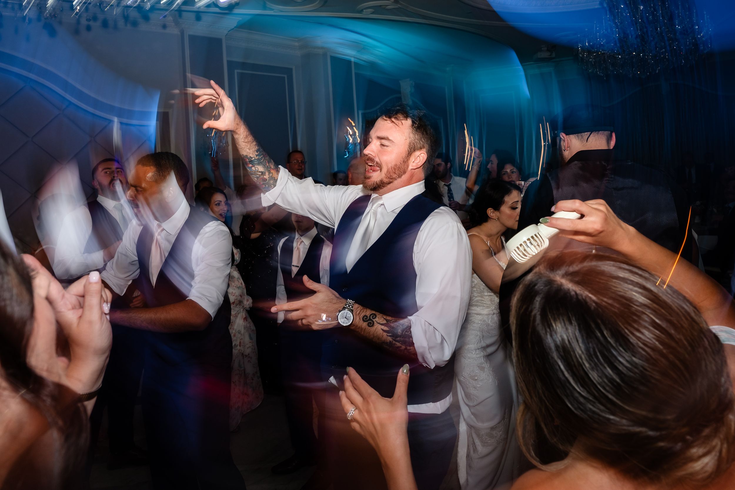 Energetic wedding guest dancing and celebrating on the dance floor during wedding reception.