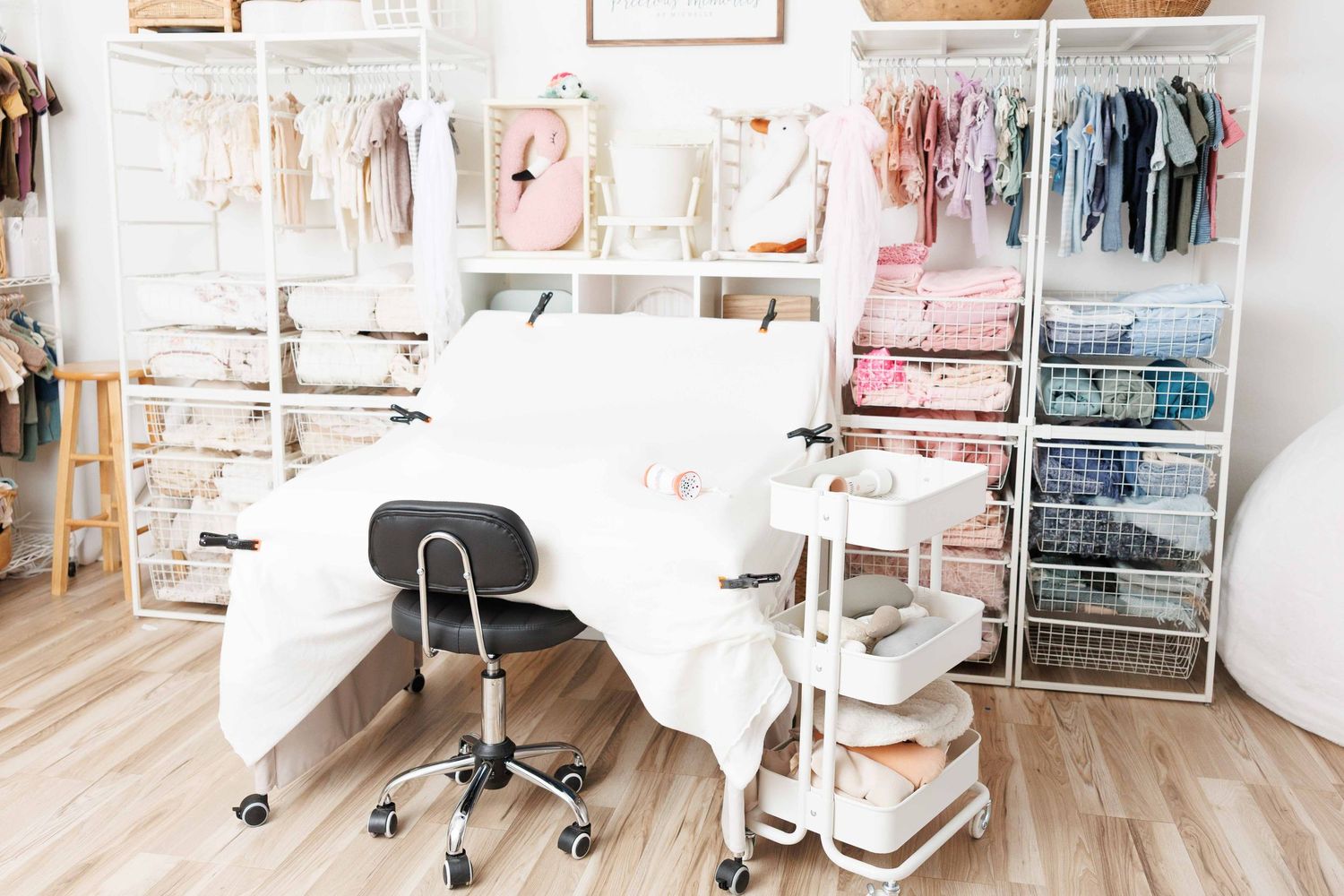 A boutique closet with packed clothing racks of pastel dresses, shelves, and a round woven rug on the floor.