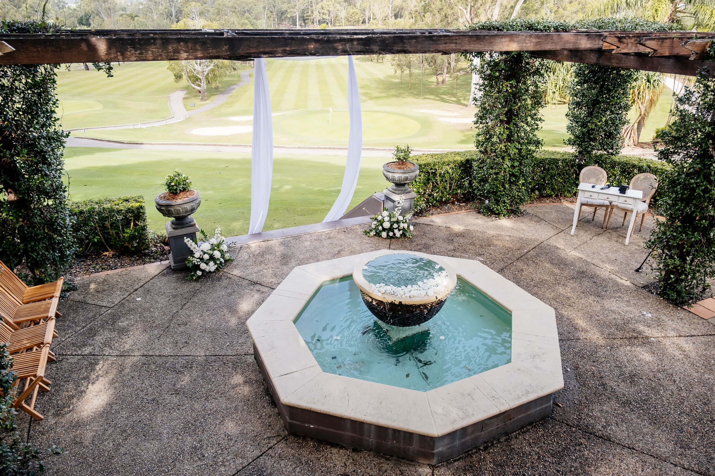 Elegant outdoor wedding venue with octagonal fountain, ivy-covered pergola, floral arrangements, at Hillstone St Lucia Brisbane