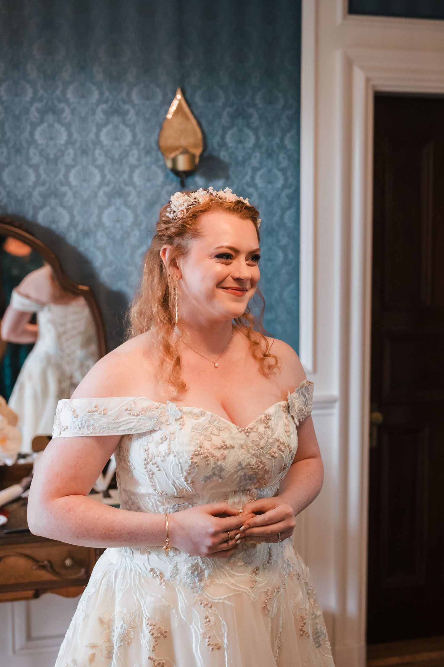 Bride smiling in her wedding dress, waiting for her father to see her for the first time.