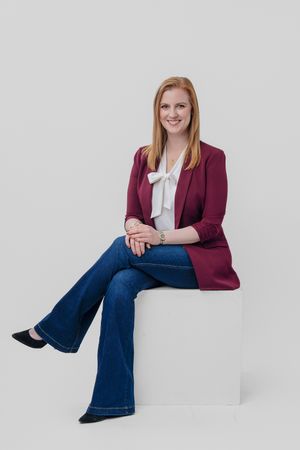 Professional headshot series showing burgundy blazer and white blouse paired with flared jeans against white backdrop.