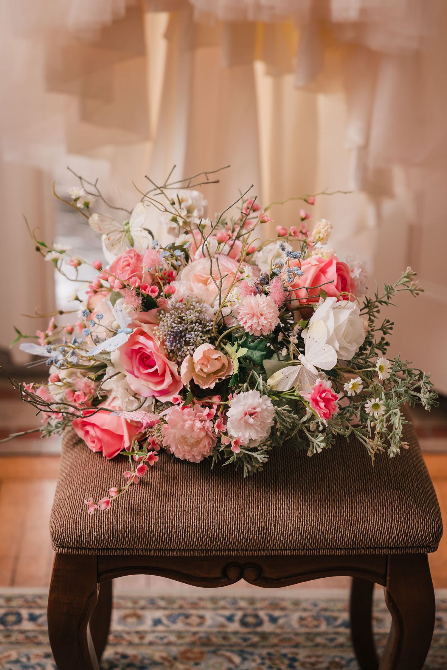 Bride's wedding bouquet with pink garden roses, wildflowers, and delicate butterfly accents, displayed at Searles Castle.