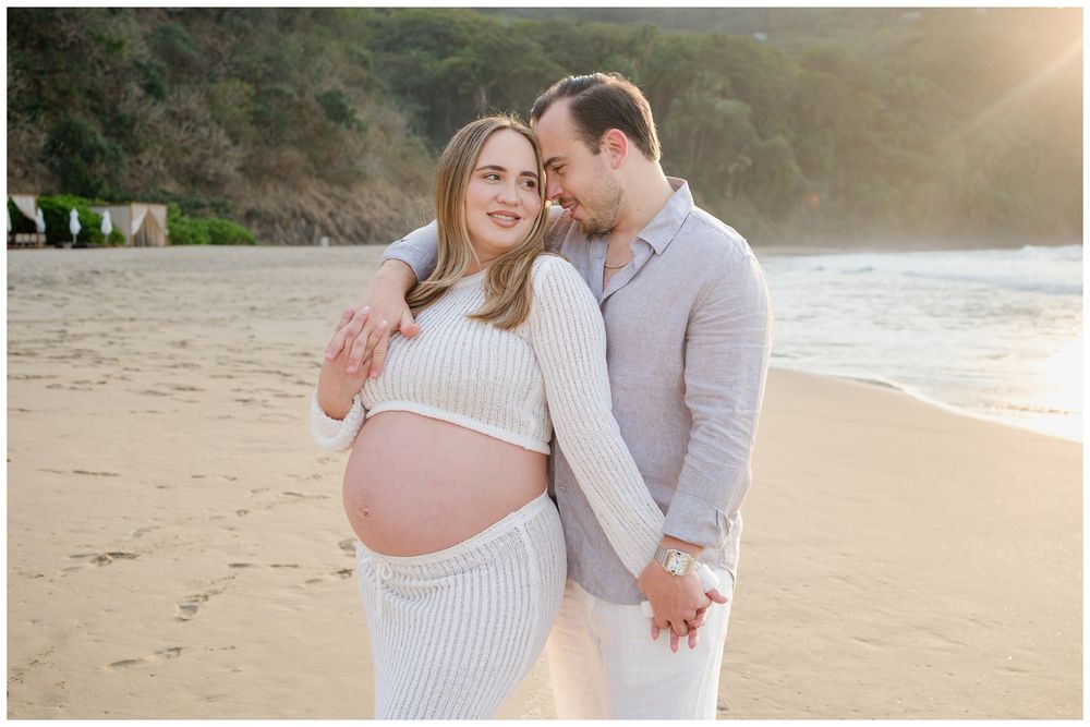 One & Only Mandarina family photographer creating timeless maternity photos for a couple on the beach at sunset.