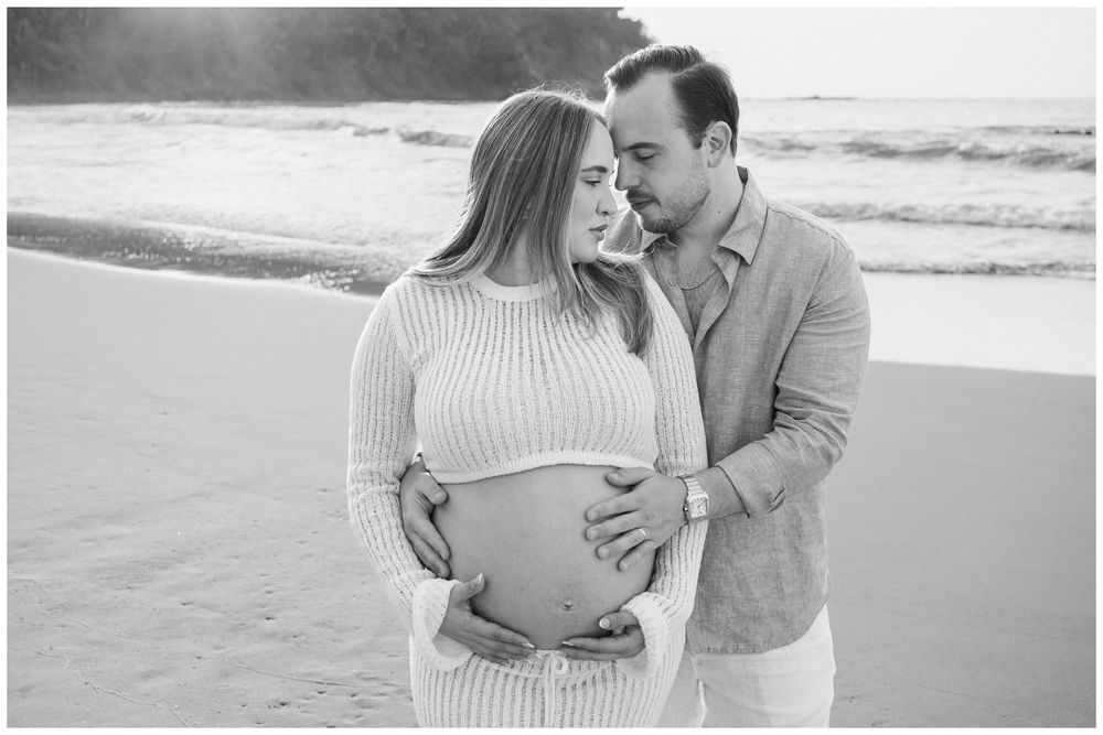 One & Only Mandarina family photographer capturing maternity photos of an expecting couple by the ocean shoreline.