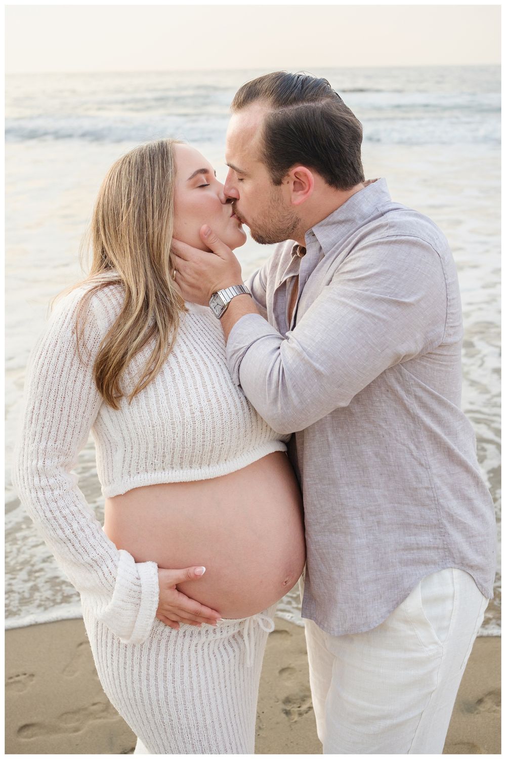 One & Only Mandarina family photographer capturing maternity photos of a couple sharing a beach moment by the ocean.