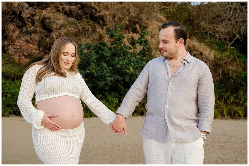 One & Only Mandarina family photographer offering maternity photos with a couple sharing a quiet beach moment surrounded by ocean views.