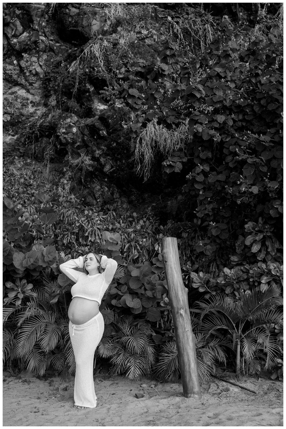 One & Only Mandarina family photographer featuring maternity photos of an expecting mother on a sandy beach with tropical foliage.