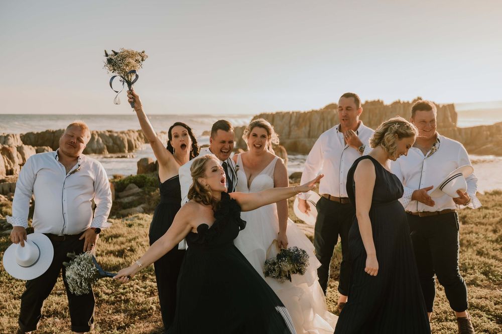 Bride and groom sharing a playful and silly moment with their bridal party at Gourikwa Reserve, capturing the laughter and fun