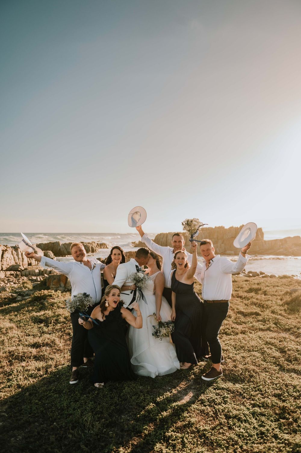 Bride and groom kissing as their bridal party celebrates at, capturing a joyful Garden Route wedding moment filled with love and laughter