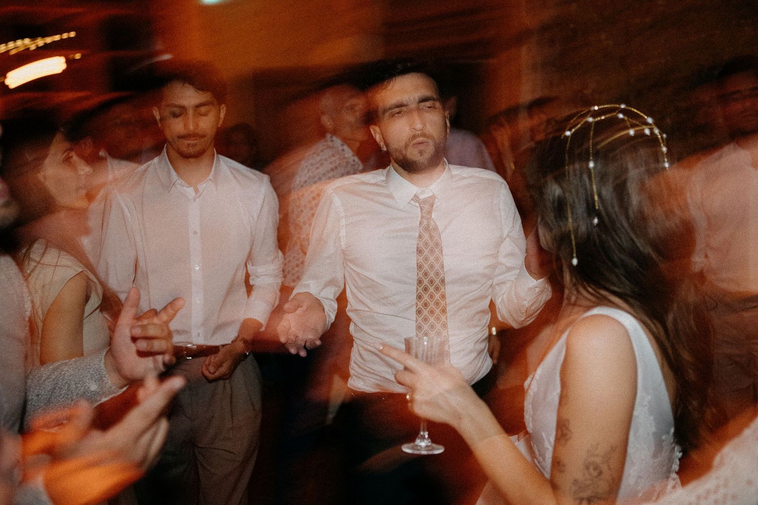 Bride and groom dancing joyfully with guests at a lively wedding reception celebration.