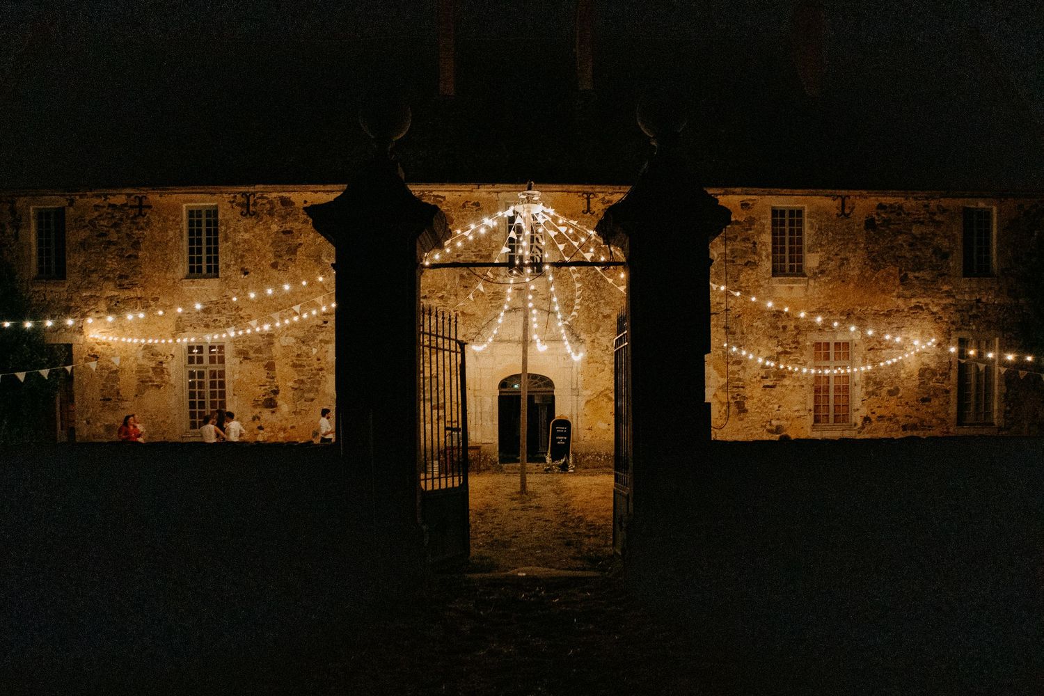 Stone building illuminated with fairy lights and string lights at night, creating a warm romantic glow.