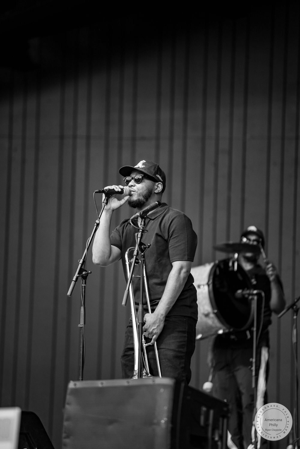 Black and white photo of male vocalist singing into microphone on stage during live performance.