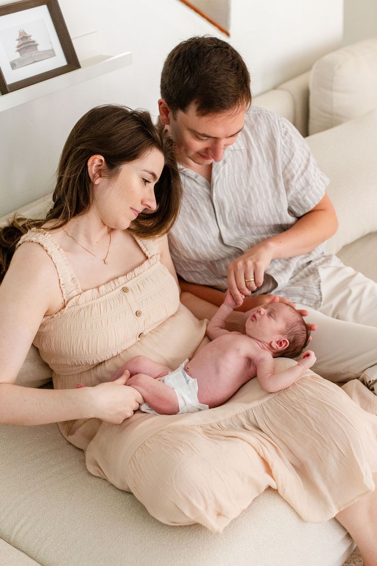 Portrait of a mother, father, and newborn asleep in mother's lap. In-home lifestyle newborn session in Guaynabo, Puerto Rico.