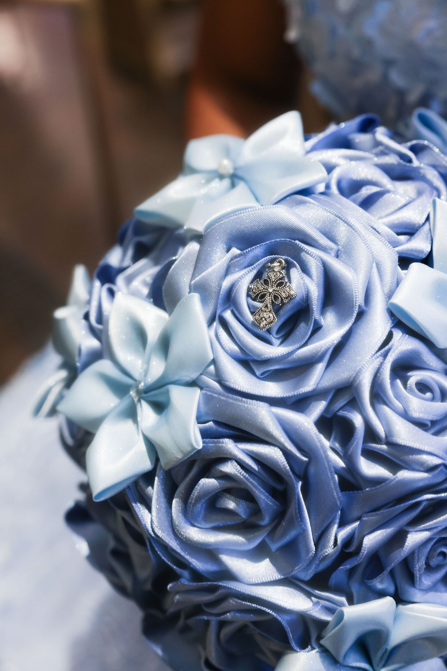 Blue satin rose bouquet with a sparkling jewel brooch centerpiece, perfect for weddings.