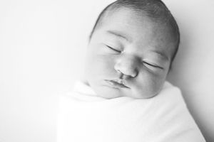Close-up portrait of a peacefully sleeping newborn baby wrapped in a white blanket