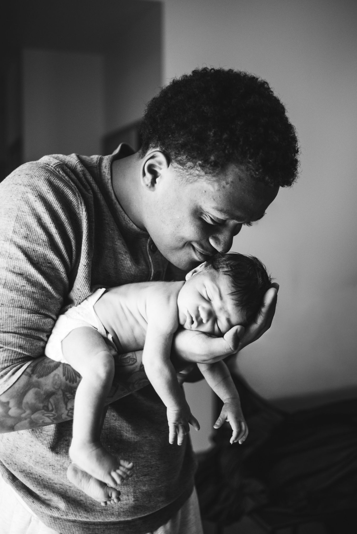 Black and white portrait of a father gently holding his newborn baby