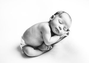 Black and white portrait of a peacefully sleeping newborn baby curled on their side