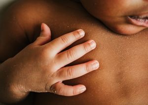 Close-up of a baby's hand resting against their body