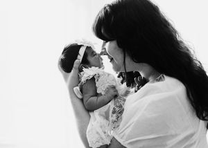 Black and white portrait of a mother gently holding her newborn baby close to her face
