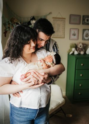 Parents holding and cuddling their newborn baby together at home during an in-home newborn session