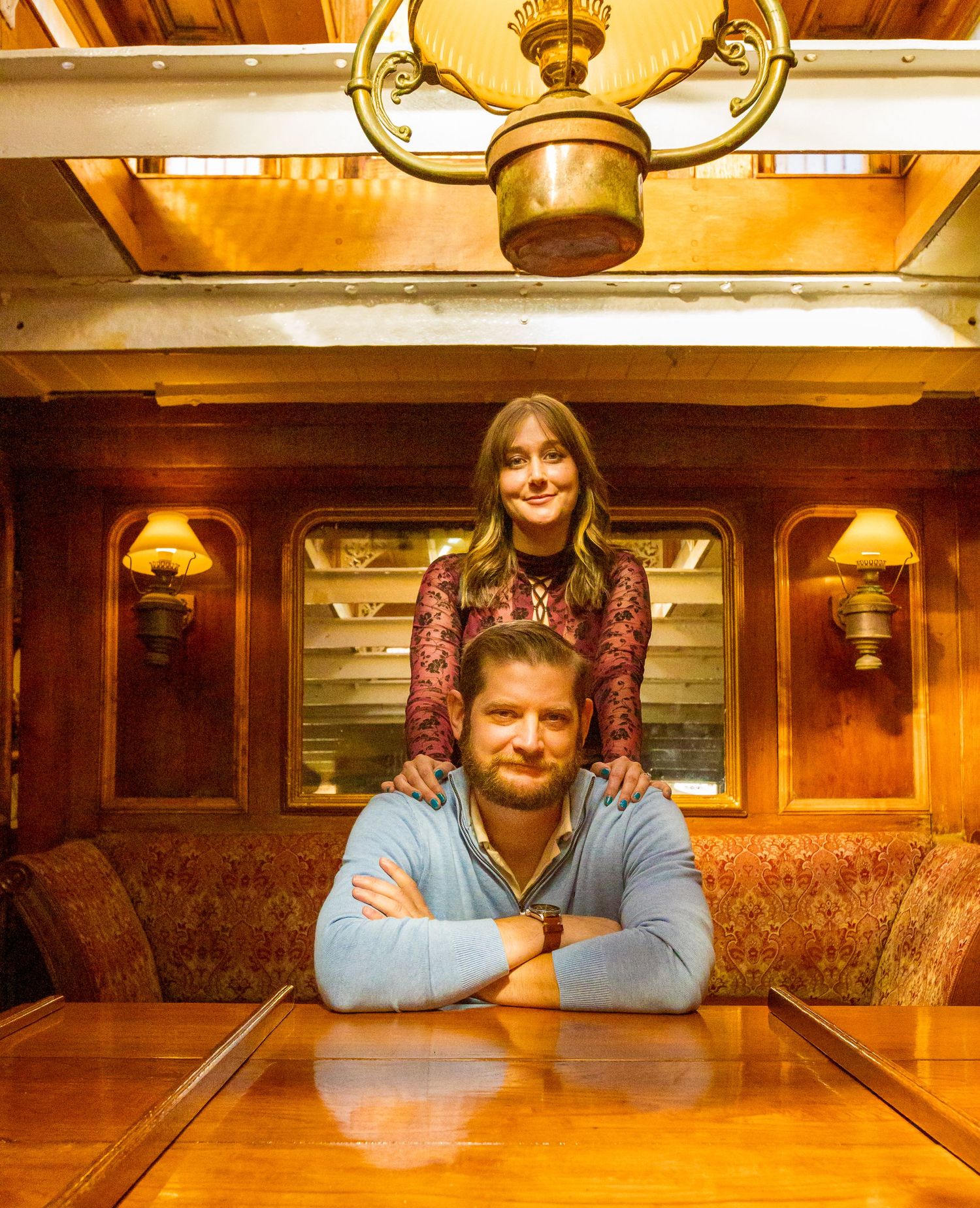 Couple embracing romantically on a tall ship deck at night with illuminated red sails in the background.