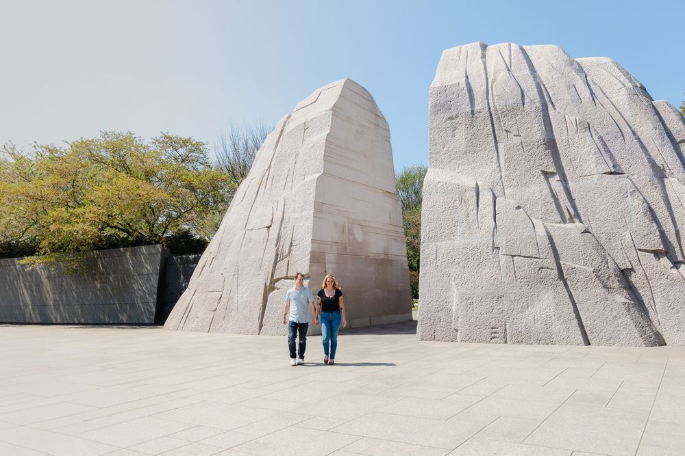 Couple walking hand in hand at the Martin Luther King Jr. Memorial, with large granite stone slabs in Washington D.C.