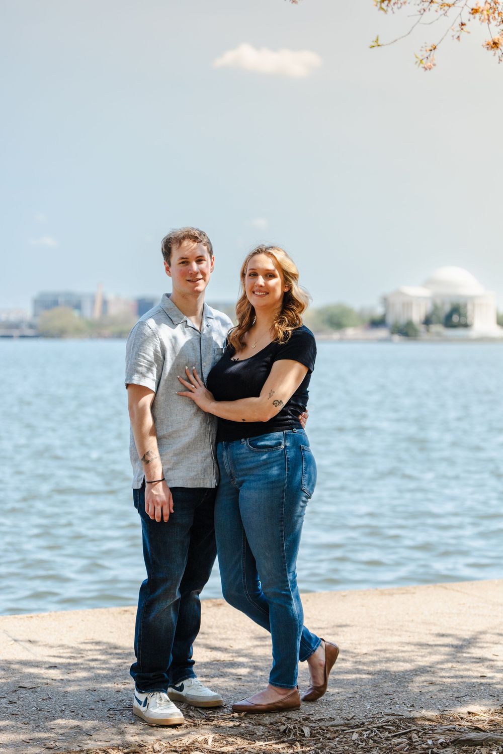 Couple posing together near the Tidal Basin with the Jefferson Memorial in the background on a sunny day.